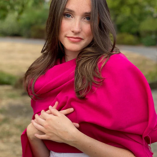 Girl wearing a soft magenta pink cashmere pashmina around her neck in a lush green field